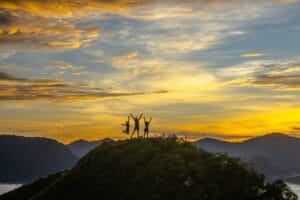 Three people celebrate atop a mountain in Panama at sunset, capturing the essence of adventure and nature's beauty.